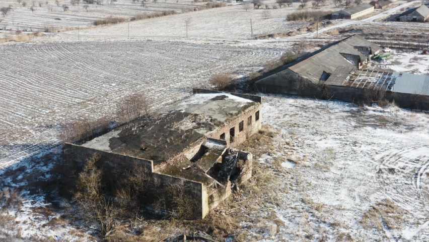 Aerial view of an abandoned industrial building near the agricultural field. Winter time