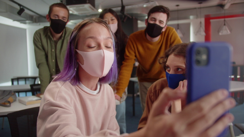 Five energetic young classmates in the audience in the university finish talking with their friends on the video call