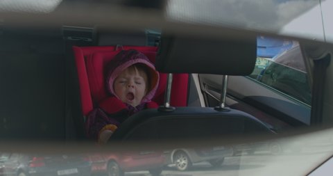 Cute little toddler yawns sweetly in a car seat. Baby sleep schedules through the first year. CZ, Velka Dobra, Karlovarska 10.04.2022 
