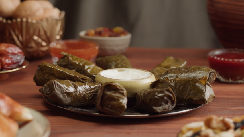 Eating dolma close-up, meat in grapes leaves with sour cream. Muslim family dinner, Ramadan, iftar. Arabian cuisine. Religious holiday, holy month. Worship and culture. Traditional Eastern Halal food Royalty-Free Stock Footage #1089168275