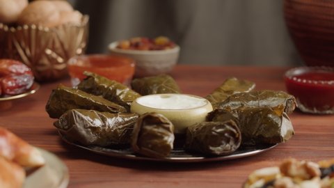 Eating dolma close-up, meat in grapes leaves with sour cream. Muslim family dinner, Ramadan, iftar. Arabian cuisine. Religious holiday, holy month. Worship and culture. Traditional Eastern Halal food
