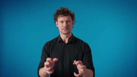 Portrait furious curly man aggressive gesture trying strangle kill posing isolated on blue studio angry business male annoyed having negative emotion mad grimace quarrel conflict communication