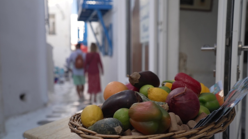Restaurant presentation and couple walking in narrow street, Mykonos Town, Mykonos, Cyclades, Greek Islands, Greece, Europe