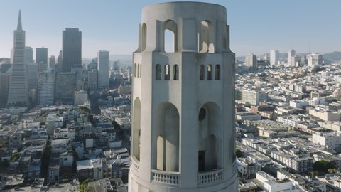 Beautiful, modern and old architecture along hillsides with lush greenery as seen from above. Drone footage of Coit Tower historic landmark in vibrant city of San Francisco. High quality 4k footage