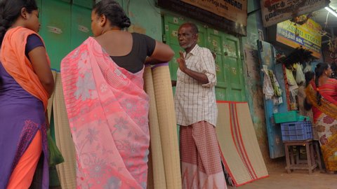 Puducherry, India, April 2020 - An old man selling jute chatai - Local market, street vendor, small business . Women buying mat from the local shop - Earning a livelihood, evening shopping, Pondy,...