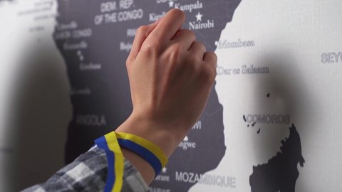 World map hand shows the country ukraine on the world map. The index finger of the girl's hand leads in the direction of Ukraine. Ukraine on the world map. Symbol of ukraine blue yellow color flag 