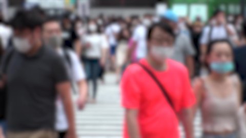 SHIBUYA, TOKYO, JAPAN - AUG 2020 : Crowd of people wearing surgical mask to protect from Coronavirus (COVID-19) at Shibuya Crossing. Shot in hot summer season. Blurred shot. Japanese medical concept.