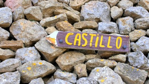 Wooden Arrow Sign With "Castillo" Word On The Pile Of Rocks