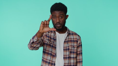 African american man showing loser gesture and pointing on you, blaming accusing for unsuccess, expressing disrespect, mocking your failure, bullying abuse. Young guy on blue studio wall background