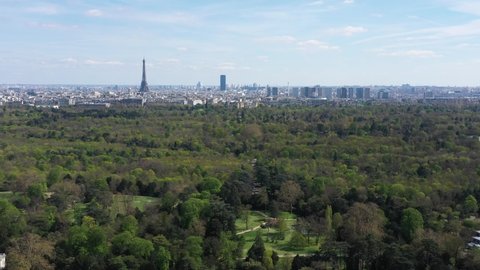 France, Paris, Boulogne wood (Bois de Boulogne) with Eiffel Tower (Tour Eiffel) and Montparnasse Tower in back. Drone aerial view during a sunny day with green trees and blue sky.