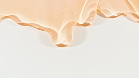 Yellow Transparent Cosmetic Gel Fluid With Molecule Bubbles Flowing On The Plain White Surface. Macro Shot of Natural Organic Cosmetics, Medicine. Production Close-up. Slow Motion