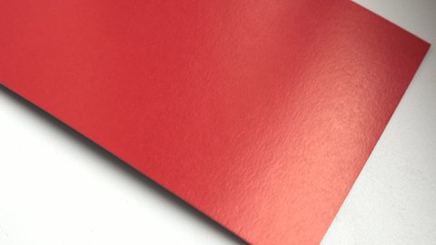 4k video, close-up, one sheet of red paper rotating on a white background, top view.