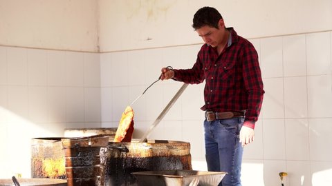 Worker gentleman boy preparing making and cooking rich and delicious typical dish carnitas food pork pork in lard oil