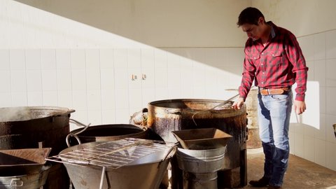 Worker gentleman boy preparing making and cooking rich and delicious typical dish carnitas food pork pork in lard oil