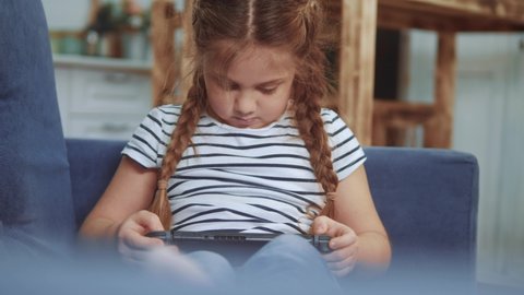 little girl playing handheld a game console. kids dream stay home computer addiction. girl playing tablet online games. addiction to online games addict kid. child play game console fun dream