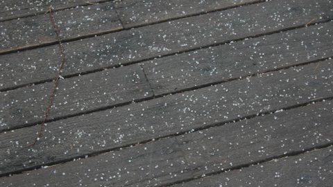 Small hailstones fell on the floor of an old, unpainted wooden deck.