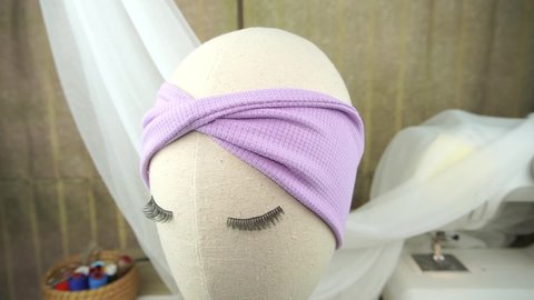 A mannequin with headband with twist pattern made out of stretch jacquard fabric in soft purple color, great as hair accessories for babies and kids.