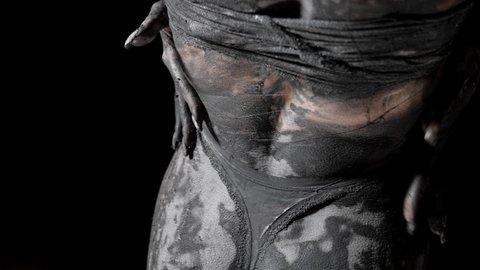 sexy woman body covered by silver dye and clay, lady is stroking her skin rear view