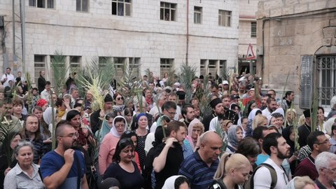 Jerusalem, Israel Apr 10, 2022: Large group of Christians with palm tree leaves walks along Jerusalem street on Palm Sunday. Entry of Our Lord into Jerusalem holiday