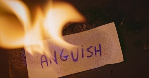 Closeup video of burning paper with ANGUISH written on it