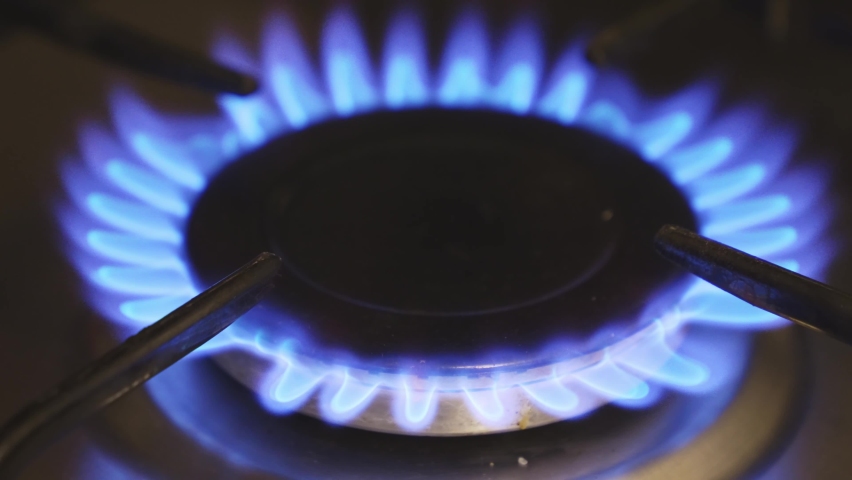 La llama azul del quemador de gas de la estufa de la cocina en la  oscuridad. coloque debajo del texto.