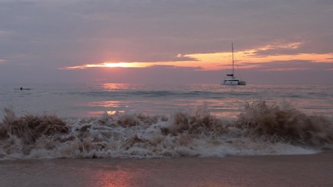 Sea Wave Water Foam Splash Washing Sandy Beach At Sunset. The yacht floats in the sea. Sundown Vacation Background.
