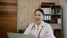 4K,50f Asian female doctor sits and talks with a patient about her illness via a laptop computer in hospital, with a happy smiling face, health and medical concepts