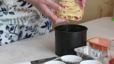 The woman puts the cruffin in a baking dish. Prepares cruffin with raisins and candied fruit. Tools and ingredients are laid out on the table