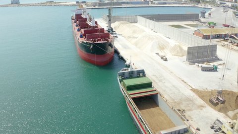 ALICANTE, SPAIN – NOVEMBER 26, 2021. Aerial view of giant cranes loading a pair of bulk-carriers in the port of Alicante.