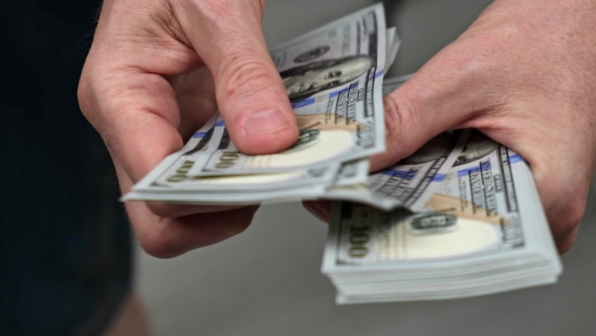 Close-up of male hands counting a stack of hundred-dollar US banknotes. a businessman is counting cash. the concept of investment, money exchange, bribes or corruption. selective focus.