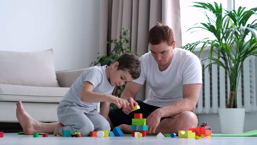Playtime. kid boy and father play builders in nursery at home. dad playing colorful blocks with his little son, boy building big tower, spending free time together at home interior. Royalty-Free Stock Footage #1089221205
