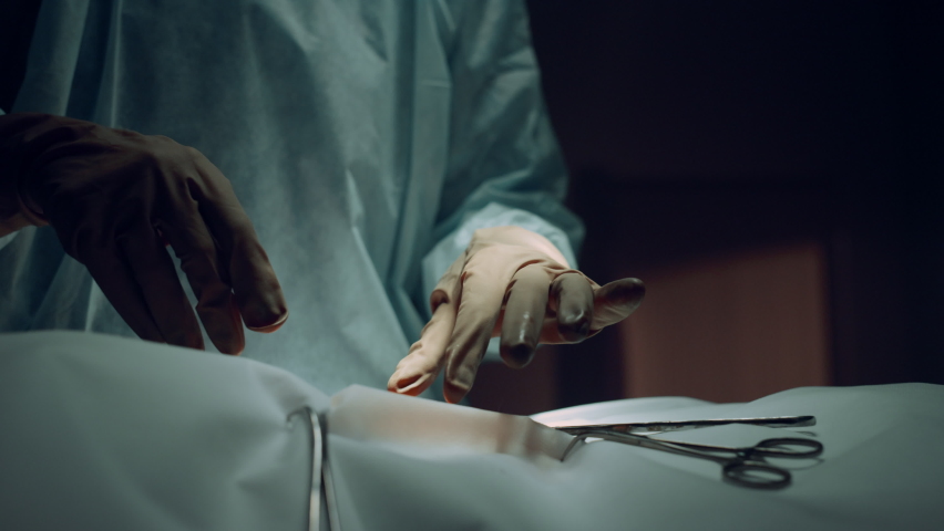 Assistant handing surgery tools to practitioner dark operating theater closeup. Unknown professional surgeon perform serious surgical operation in clinic intensive care unit. Surgery process concept. Royalty-Free Stock Footage #1089222459