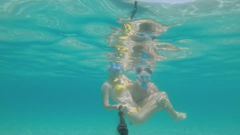 Selfie of a young couple swimming underwater in a tropical lagoon. Two people have fun with an underwater camera while filming their vacation. Slow motion