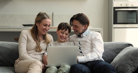 Bonding family mom dad teenage child son cuddle on comfortable sofa watch funny movie cartoon on laptop together. Happy couple with preteen age kid boy laugh on cute photos at social networks using pc