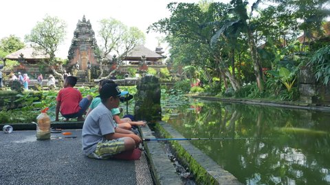 BALI, INDONESIA - JANUARY 28, 2018: Asian boys fishing at the lotus pond in Ubud near the temple - 4K, Editorial. Ubud Water Palace.