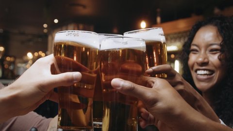 Multi-ethnic group of friends clinking glasses of beer at a restaurant.: stockvideo