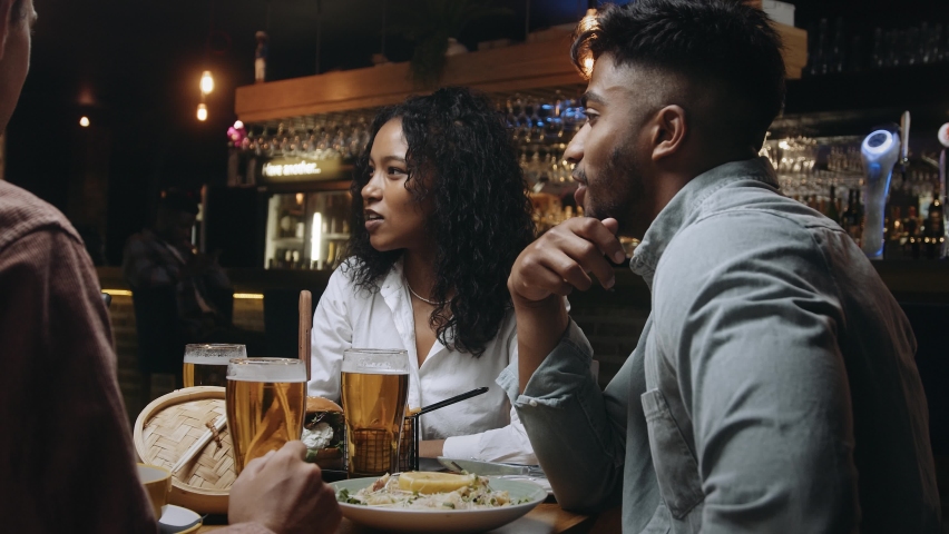 A multiracial woman having dinner and beers with a group of friends at a restaurant and laughing at something her friend said Royalty-Free Stock Footage #1089230161