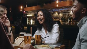 A multiracial woman having dinner and beers with a group of friends at a restaurant and laughing at something her friend said - Powered by Shutterstock - Get 15% off with code: PIKWIZARD15