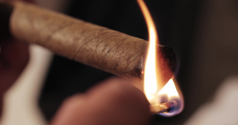 Men's hands twist and set fire to a Cuban cigar with a match in their hands. macro | Shutterstock HD Video #1089230943