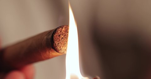a match is burning and setting fire to a Cuban cigar. man's hands light a cigarette. macro
