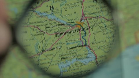 War in Ukraine. Look at map with magnifying glass close up near Dnipro, Zaporizhya, Kryvyi Rih, Pavlograd, Nikopol. Ukrainian language paper map