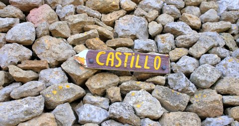 Wooden Arrow Sign With "Castillo" Word On The Pile Of Rocks. Slide Shot