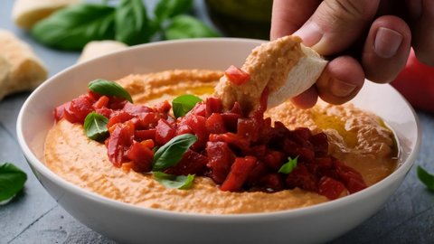 Eating roasted red pepper hummus with pita bread.