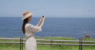 Woman take photo on cellphone beside the sea