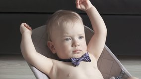 Cute small child face closeup, one year old baby boy wearing a bow tie lying in rocking chair for kids. High quality 4k footage