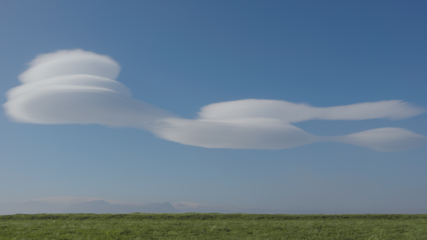 Wide Drone Flight Pulling Back Over Green Landscape Towards White Soft Stratus Clouds In Deep Blue Sky, Iceland