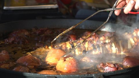 Traditional Polish boneless pork knuckles and kebabs are simmering in a large frying pan at the Easter Food Festival at the Market Square in Krakow