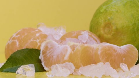 Tangerine whole on the table on a yellow background, water drop falling on the fruit. Slow motion, 8K downscale, filmed on high speed cinema camera. 4K.