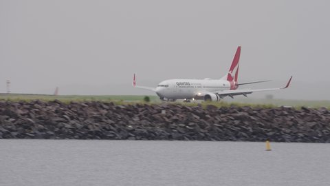 Sydney, Australia - Mar 24, 2022: Qantas airplane landing at Sydney airport in the rain