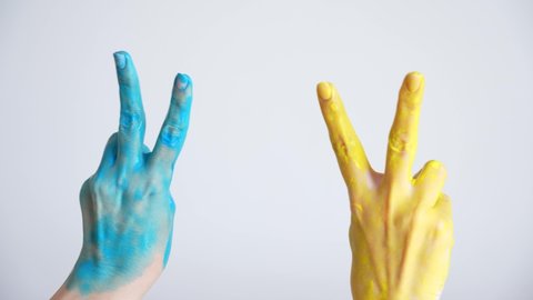 Close-up view 4k stock video footage of two female hands painted in blue and yellow colors of ukrainian national flag. Happy adult woman showing V letter or victory sign or symbol gesture both hands